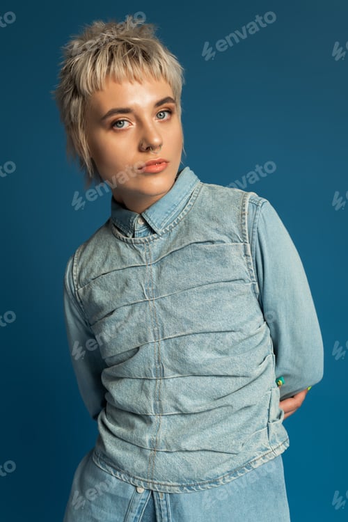Preview: Stylish young woman poses confidently against a vibrant blue background showcasing her fashion sense