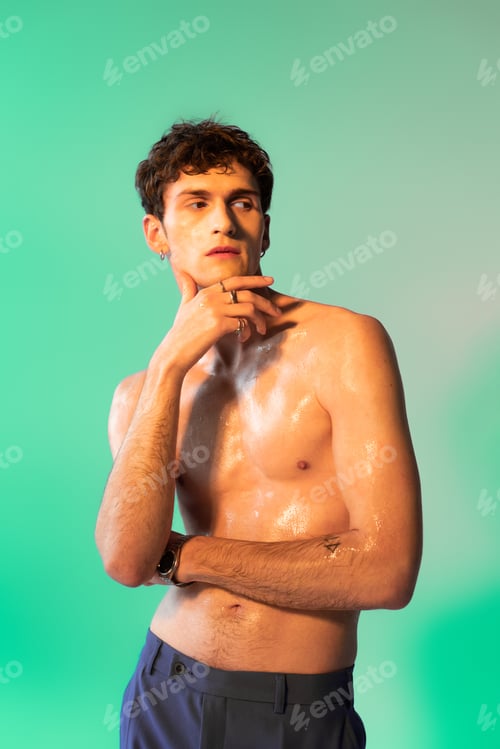Preview: Shirtless man with oil on body posing and looking away on green background