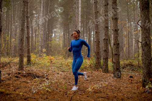 Preview: Young woman running toward camera on the forest trail at autumn