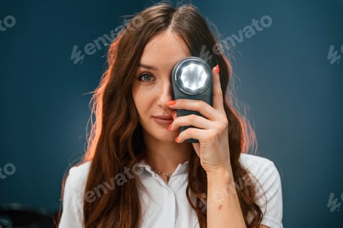 Preview: Woman cosmetologist is holding device with light