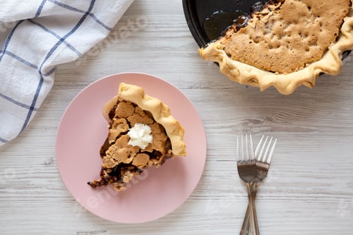 Preview: A slice of homemade Chocolate Walnut Derby Pie on a pink plate on a white wooden surface, top view.