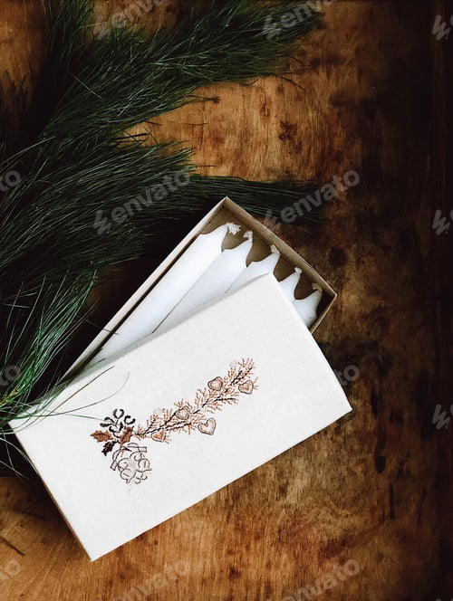Preview: Christmas gift box with embroidery, fir branches and white candles lie on a wooden table, top view.