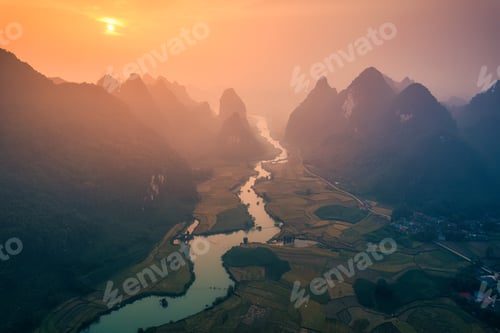 Preview: Golden sunrise over mountain range with winding river on agricultural village at Phong Nam Valley