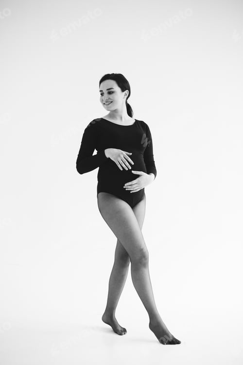 Preview: Beautiful young pregnant woman posing in studio in dress