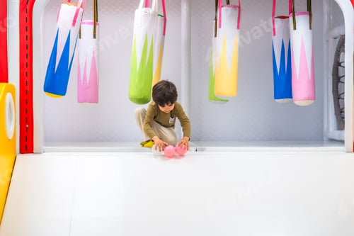 Preview: Boy playing with balls in soft play area with punching bags