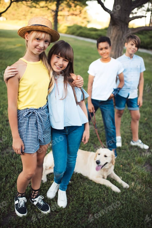 Preview: smiling teenage girls embracing and smiling at camera while multiethnic boys with dog standing