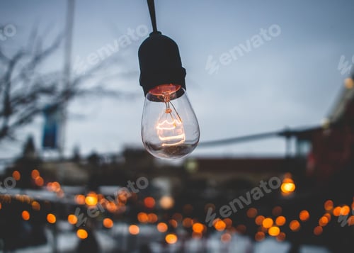 Preview: Light bulb hanging in the dark with a city behind them