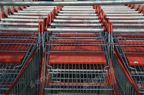 Preview: Closeup of rows of stacked metal shopping trolley carts with red handles