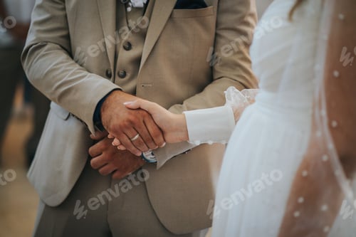 Preview: Groom and bride holding hands in a church during their wedding ceremony