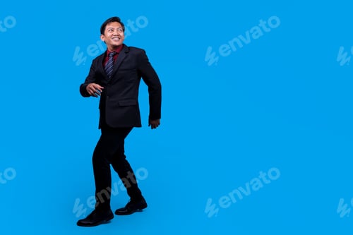 Preview: Confident Young Businessman Walking Happily In Modern Business Attire Against Blue Background