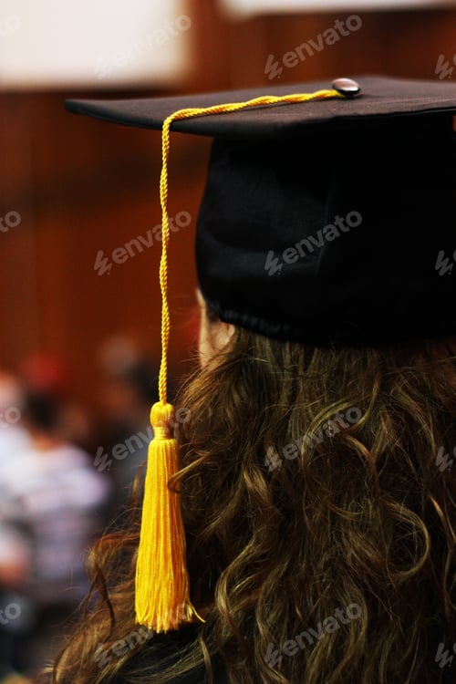 Preview: Young woman student at her graduation. Yellow tassel