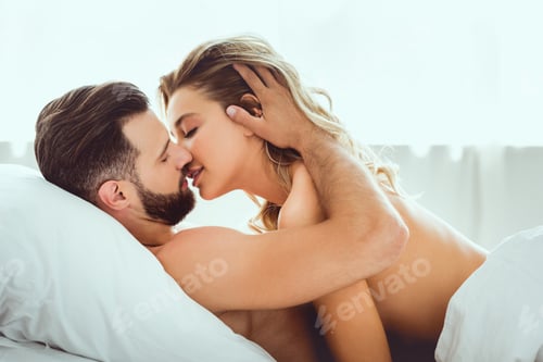 Preview: handsome young man kissing beautiful girlfriend while lying in bed