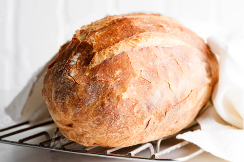 Preview: Freshy baked homemade bread on a light grey marble table decorated textile towel