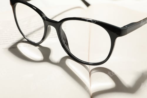 Preview: Heart made of shadow and glasses on opened book, close up