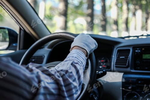 Preview: Soft focus of a driver's hand wearing gloves, on a steering wheel