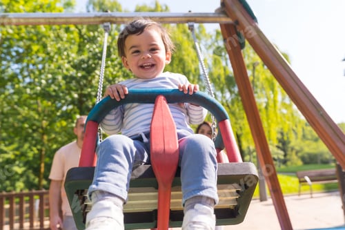Preview: Baby boy in a swing laughing next to his parents