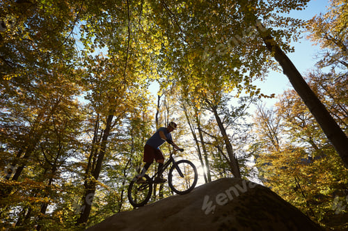 Preview: Male cyclist on trial bicycle on the top of boulder outdoors