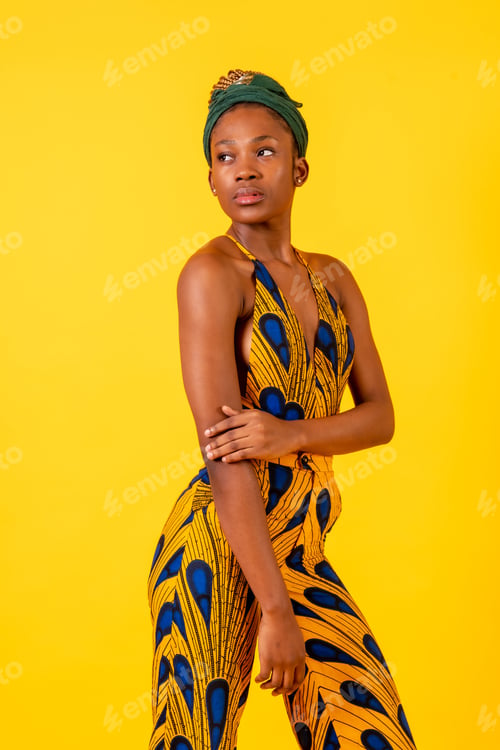 Preview: African young woman in the studio on a yellow background, portrait in a traditional costume