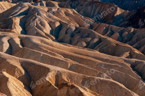 Preview: Sunlight graces the textured landscape of a rugged desert canyon.