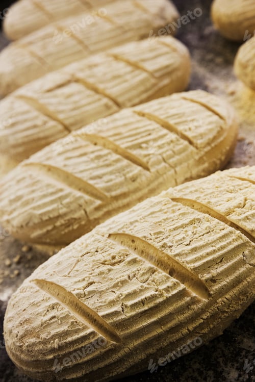 Preview: Close up high angle view of bread dough shaped into loaves, dusted with flour.