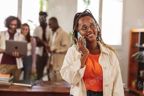 Preview: African woman in the office engaged in a confident conversation on her mobile phone,