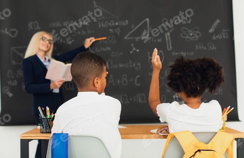 Preview: A female teacher teaches schoolchildren at the blackboard in the classroom. International team.
