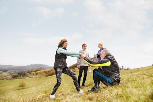 Preview: Group of active senior runners outdoors, resting.