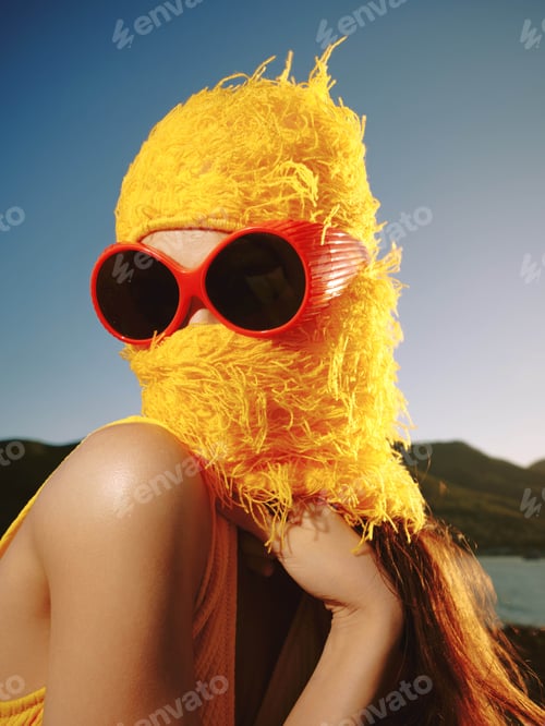Preview: A woman in sunglasses and a yellow hat partially covers her face while sunlight filters through the