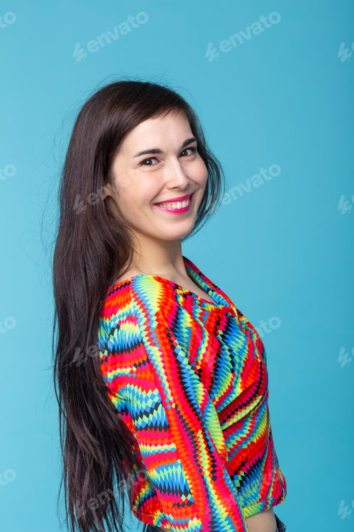 Preview: Smiling charming young brunette woman standing against a blue background. Concept of carefree young