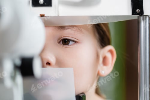Preview: close up view of kid examining eyesight on blurred ophthalmoscope