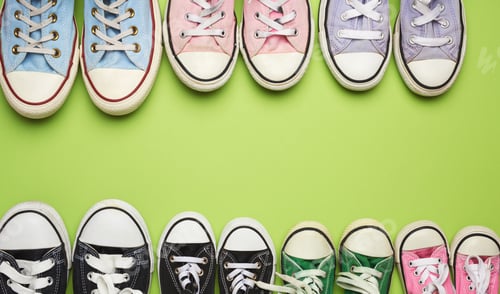 Preview: Many multi-colored well-worn textile sneakers of different sizes on a green background