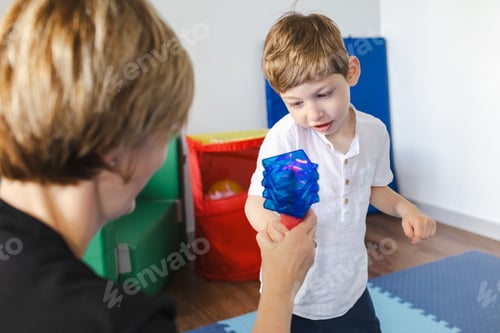 Preview: Physical therapist helps a young boy with cerebral palsy during a playful rehabilitation session,