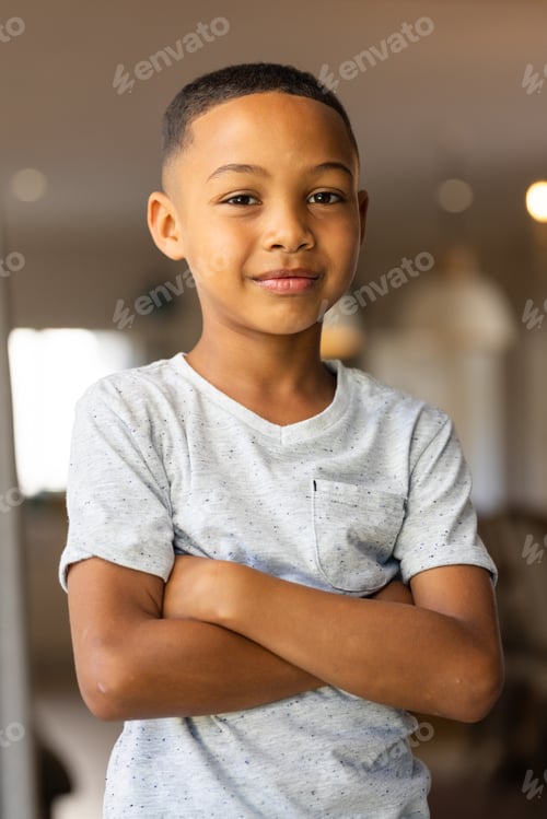 Preview: Standing confidently with arms crossed, smiling boy at home