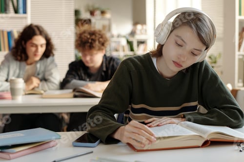 Preview: Woman Wearing Headphones in College Library Reading Book