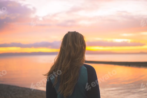 Preview: Woman looking at sunset near water