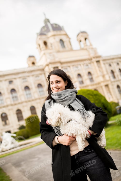 Preview: Beautiful happy young woman with cute small dog puppy have fun on street