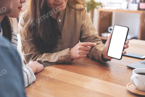 Preview: Woman holding and showing mockup mobile phone to friends