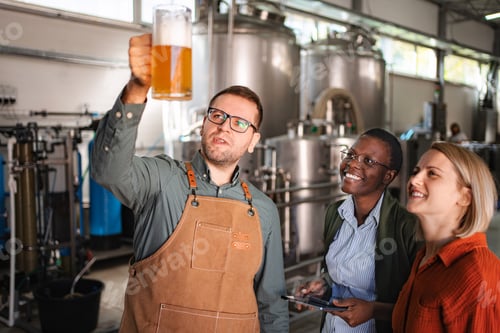 Preview: Brewer inspecting craft beer with diverse women in modern brewer