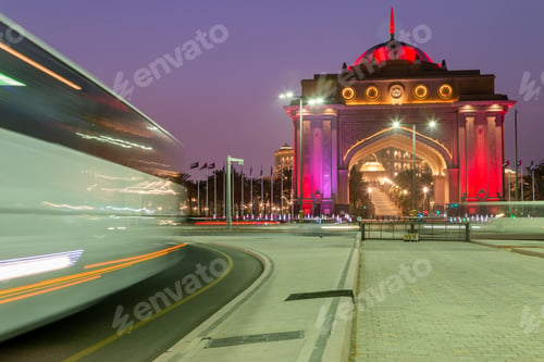 Preview: Emirates palace VIP gates illuminated in the evening. Bus passing by on the street.