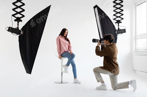 Preview: Professional photographer taking picture of young woman, having photoshoot in studio with lighting