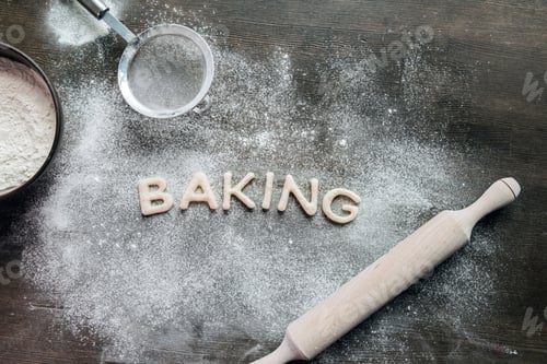 Preview: top view of cookies in forms of letters with powdered sugar and rolling pin, cookie dough
