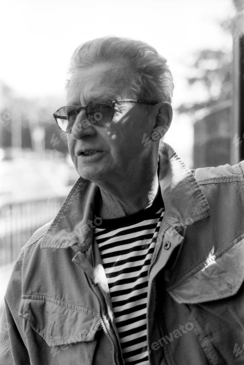 Preview: Senior man wearing sunglasses and striped shirt in monochrome analog film portrait