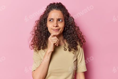 Preview: Horizontal shot of thoughtful Afro American woman holds hand on chin ponders on something focused
