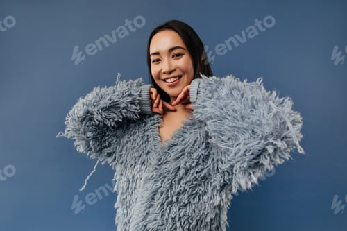 Preview: Charming asian lady with cute smile and tanned skin in fashionable fluffy sweater with long sleeve