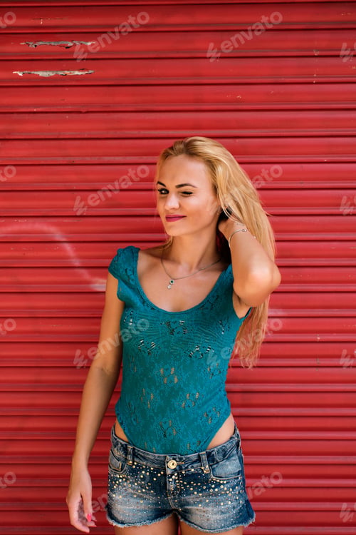 Preview: a young woman blinks an eye with a strong red background - complimentary colors - gestures concept