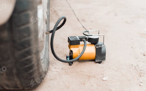 Preview: Inflating air into tire with car compressor outdoors. Close-up, selective focus on electric pump