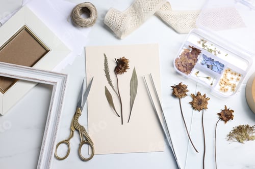 Preview: Flat lay composition with dry flowers and paper on white marble table