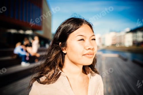 Preview: Young woman enjoying the sunshine on a city boardwalk.