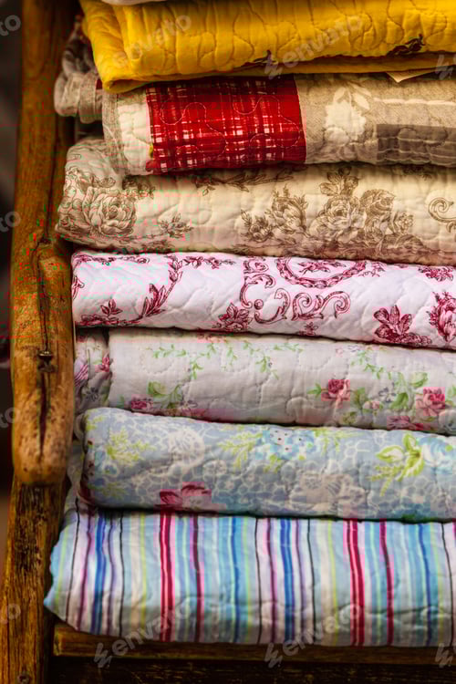 Preview: Stack of Quilted Textiles on Wooden Chair