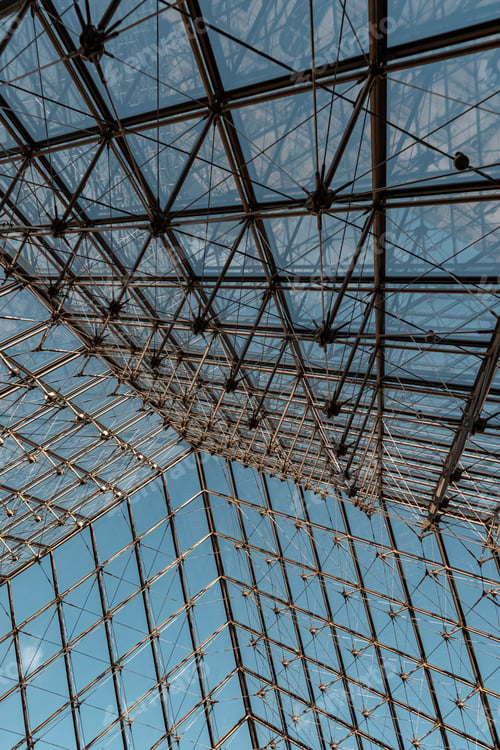 Preview: Low angle shot of the Louvre Pyramid under a blue sky and sunlight